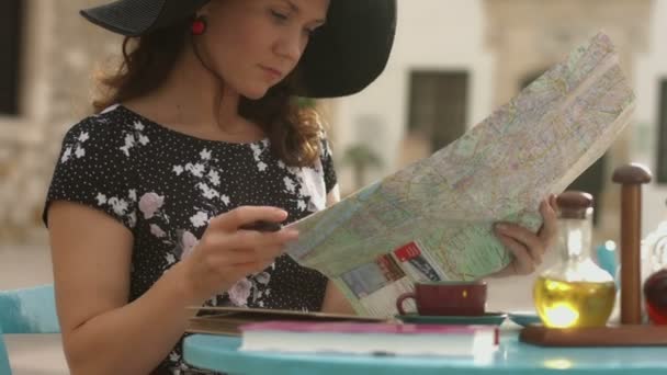 Mujer joven comprobando mapa, satisfecha con el plan de viaje, tomando notas con pluma — Vídeo de stock