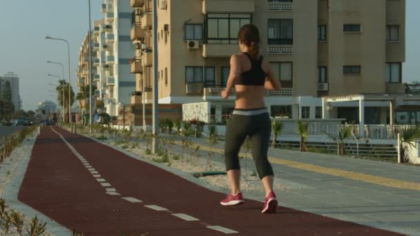 Giovane signora che corre lungo pista da jogging a piacimento. Forte motivazione al successo — Video Stock