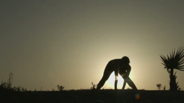 Silhouette einer aktiven Frau, die Yogapositionen praktiziert, Übungen bei Sonnenuntergang macht — Stockvideo