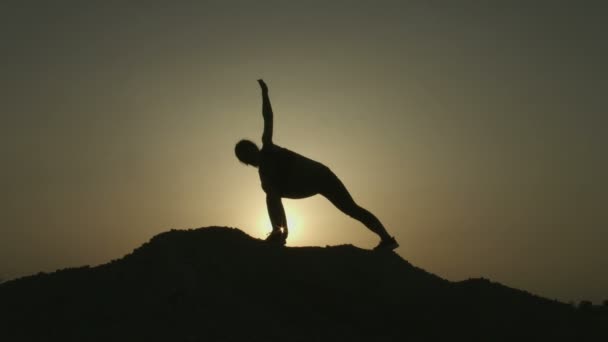 Силуэт женщины, практикующей йогу в одиночестве на вершине горы вечером — стоковое видео