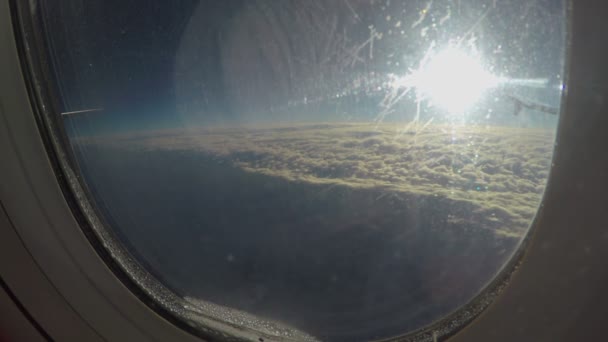 Vista del sole che splende sul paesaggio nuvoloso attraverso sporca finestra di aereo che vola nel cielo — Video Stock
