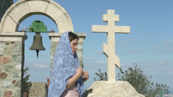 Mujer joven y pacífica rezando al aire libre cerca de la cruz de piedra, pidiendo a Dios bendición — Vídeos de Stock