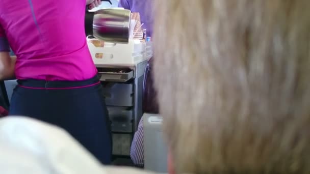 Woman in flight attendant uniform pouring coffee for passenger on board of plane — Stock Video