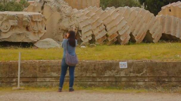 Νεαρό θηλυκό τουριστών λαμβάνοντας εικόνα από τεράστια στήλη παραμένει, περιήγηση στα αξιοθέατα — Αρχείο Βίντεο