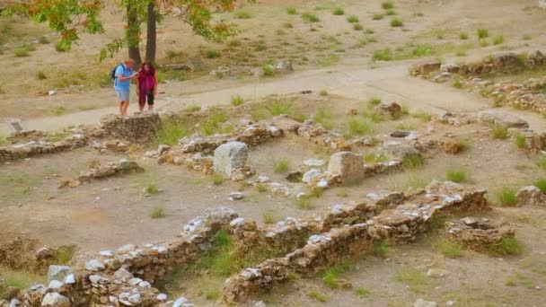 Pár turistů, při pohledu na staré kamenné nadace vyhloubil archeologové — Stock video