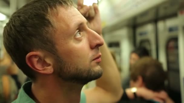 Pasajero varón cansado leyendo anuncios dentro del metro durante la hora punta — Vídeo de stock