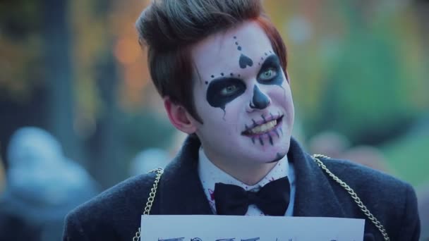 Zombie śmieszne parady w ulicy miasta, facet z wolna przytula znak uśmiechając się do ludzi — Wideo stockowe