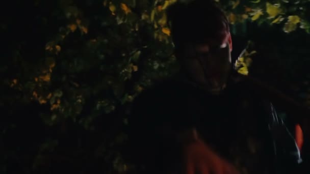 Страшный зомби, шагающий по тёмному лесу с топором на плече, кровавый кошмар — стоковое видео
