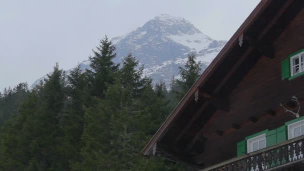 Einspielung einer schönen Holzhütte in den Bergen, schneebedeckter Felsen im Hintergrund — Stockvideo