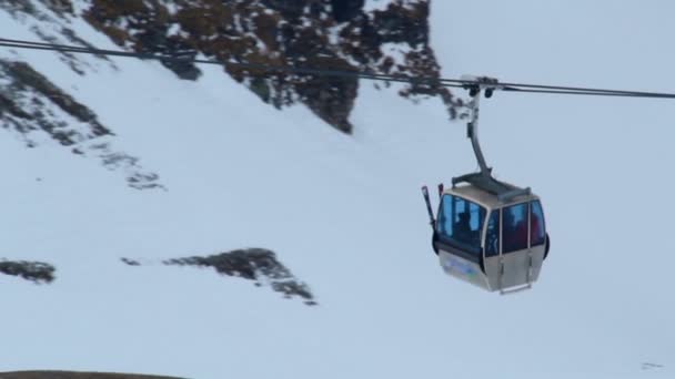 Teleferikte oturan insanlar, karlı dağlarda kayak pistine doğru ilerliyorlar.