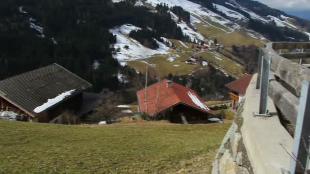 Vieille route serpentine passant petite ville de chalet sur colline de montagne, zone rurale — Video