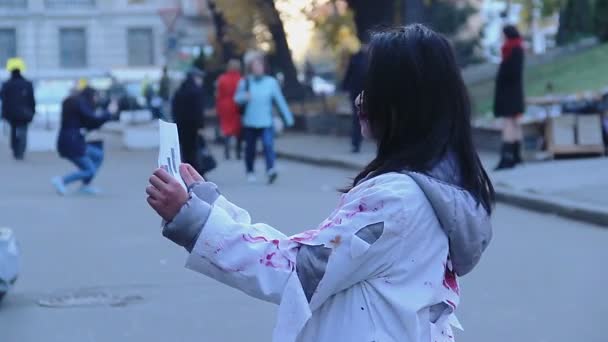 Young woman wearing zombie suit having fun with free hugs sign on Halloween — Stock Video