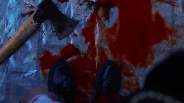 Crazy murderer dropping axe in pool of blood, leaving crime scene, horror film — Stock Video