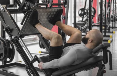 Güçlü adam fit kaslı vücut egzersizleri bacak basın makinede yapıyor ile egzersiz