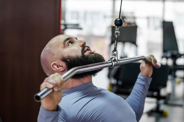 Male athlete doing exercises on pulldown machine in the gym, healthy lifestyle — Stock Photo, Image