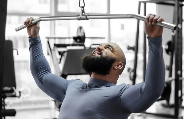 Male athlete pulling down heavy weight with strained face, sports training — Stock Photo, Image