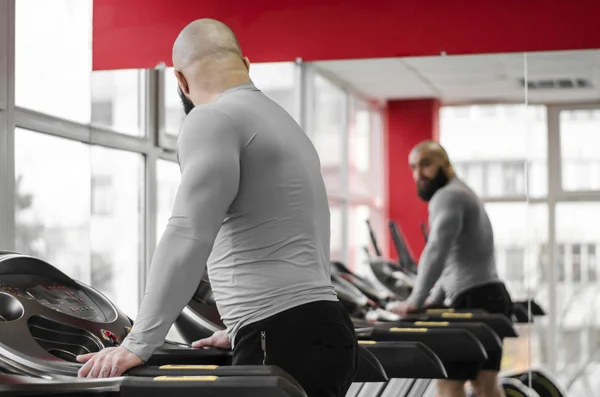 Man training on treadmill, looking at his reflection in mirror after workout — Stock Photo, Image