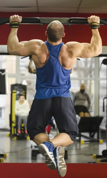 People in the gym watching as professional bodybuilder training, doing pull-ups — Stock Photo, Image