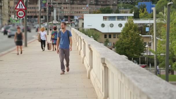 Male with backpack walking across the bridge — Stock Video