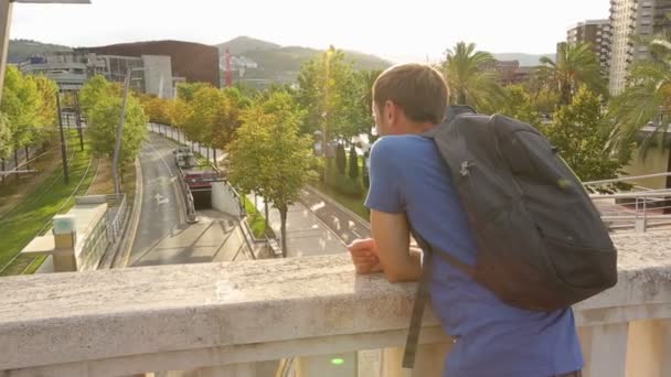 Young happy traveler standing on bridge — Stock Video