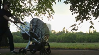 Kiev, Ukrayna - Temmuz 2015 yaklaşık: İnsanlar parkta. Bebek arabasındaki bebek ile yürüme baba, anne ve kızı paten keyfini çıkarın
