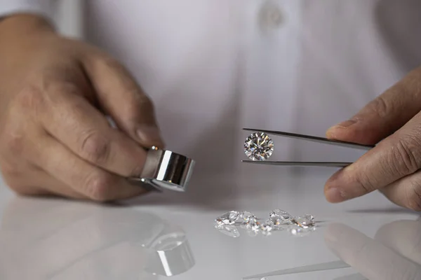 Jeweller at work holding diamond in hand. Diamond tools, loupe, tweezers. Buyer looking at diamond in jewellry store, gem shoping.