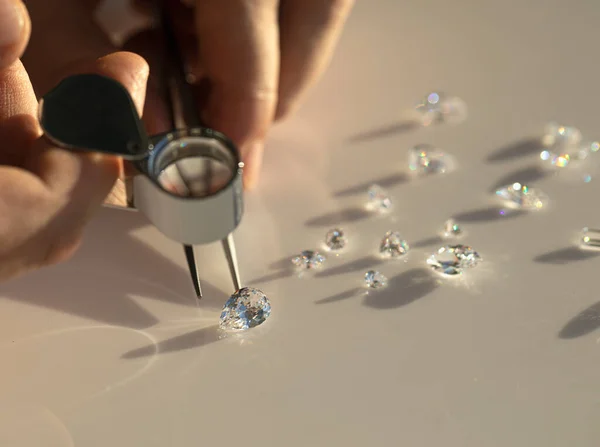 Jeweller hand holding diamonds. Diamond business in inspection and sales of brilliants. Jewelry gem precious stones. Luxury jewellery on the Sun light.