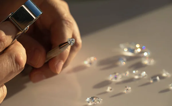 Jeweller hand holding diamonds. Diamond business in inspection and sales of brilliants. Jewelry gem precious stones. Luxury jewellery on the Sun light.