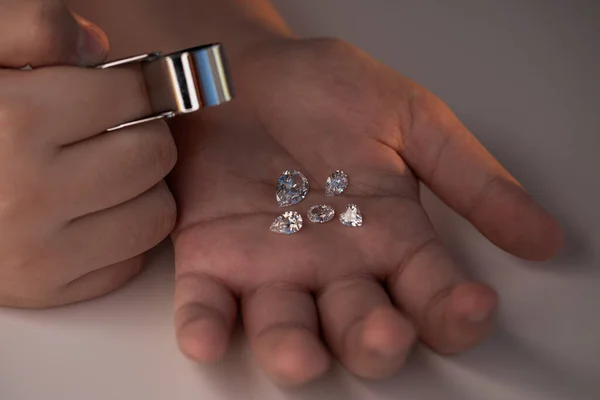 Jeweller hand holding diamonds. Diamond business in inspection and sales of brilliants. Jewelry gem precious stones. Luxury jewellery on the Sun light.