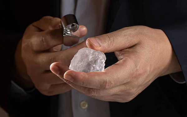 Huge piece of rough diamond on hand of diamantre. Rough diamnd on mine. Raw diamond material for cutting and polishing. Jeweller holding crystal stone.