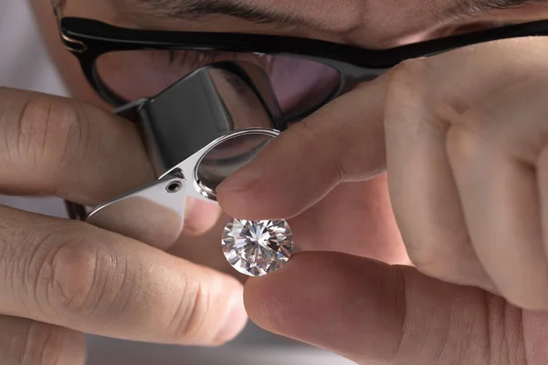 Jeweller asian man looking at diamond through magnifying glass. Diamond dealer evaluating and grading big size gem stone.