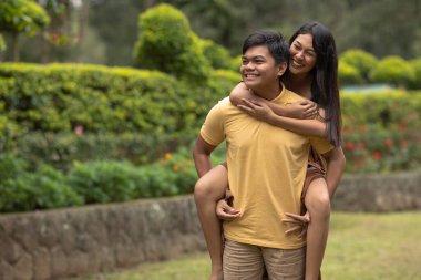 Genç ve güzel Asyalı çift parkta birlikte mutlu mesut yürüyorlar..