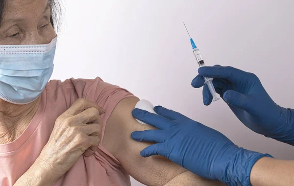 Yaşlı Asyalı kadın Covid-19 'a karşı aşılandı. Doktor şırıngaya bir doz aşı koydu. Coronavirus aşısı yaşlı konsepti.
