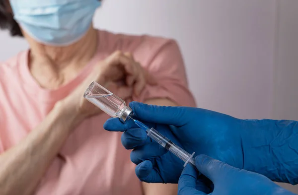 Yaşlı Asyalı kadın Covid-19 'a karşı aşılandı. Doktor şırıngaya bir doz aşı koydu. Coronavirus aşısı yaşlı konsepti.