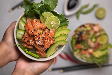 Pirinç, somon ve taze sebzeler, salatalıklar, yeşil bezelyeler ve kırmızı biberli yemek çubukları, soya sosu ve limonlu otlar. Lezzetli sağlıklı yemek...