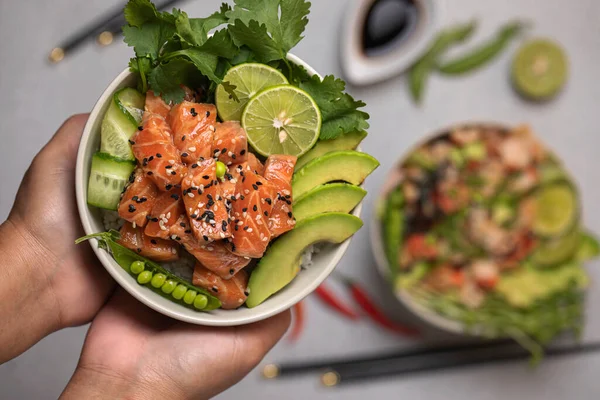 Pirinç, somon ve taze sebzeler, salatalıklar, yeşil bezelyeler ve kırmızı biberli yemek çubukları, soya sosu ve limonlu otlar. Lezzetli sağlıklı yemek...