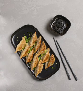 Kızarmış Japon Gyoza hamur tatlısı, siyah tabakta yemek çubukları ve soya sosu.. 