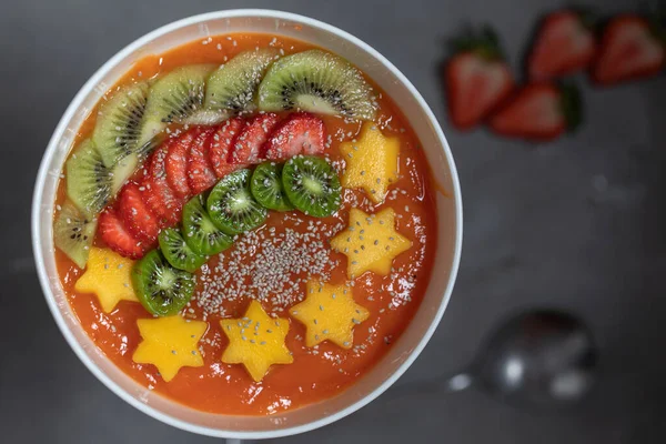 Dilimlenmiş kivili çilek ve chia tohumlarıyla süslenmiş taze papaya pürüzsüz, vejetaryen kahvaltısıyla kaseyi kapat. Sağlıklı gıda konsepti.