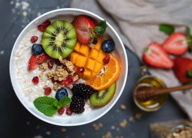 Üst manzarası renkli meyveli bir kasede yulaf ezmesi. Parlak sağlıklı kahvaltı konsepti.