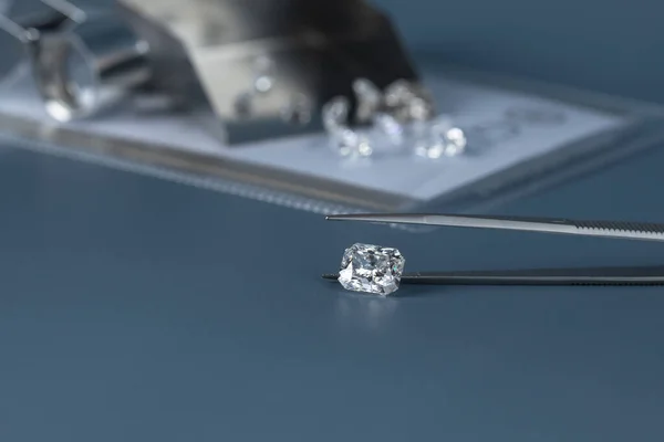 Cut diamond in hand close up with jewelry tools and scattering of different diamonds in background, front view on blue background.