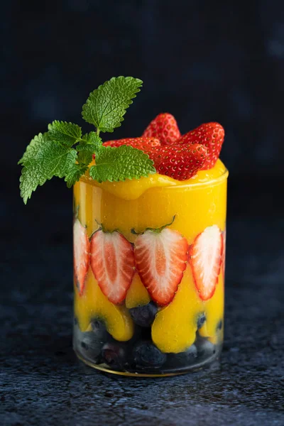 Primo piano di luminoso frullato di mango succoso guarnito con bacche e menta. Sano cibo delizioso a base di frutta fresca e bacche. — Foto Stock