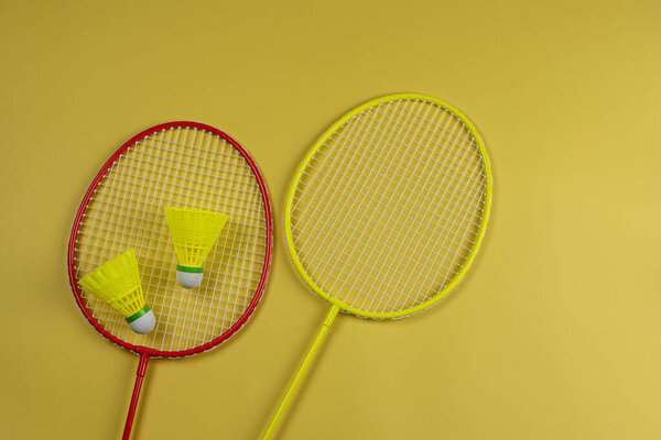 Bright rackets and shuttlecocks for badminton on yellow background flat lay top view.
