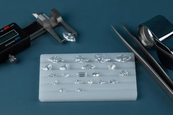 Diamanty různých velikostí na pracovišti obchodníka s diamanty vyhodnocující leštěné diamanty. — Stock fotografie