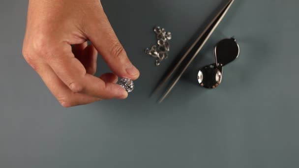 Крупный план эксперта по алмазам исследует круглый бриллиант на рабочем месте. Отснятый сверху материал. — стоковое видео