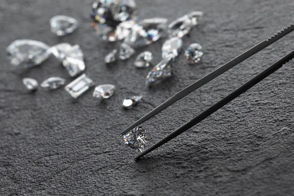 Diamants polis de différentes formes et tailles sur le lieu de travail d'expert en bijoux évaluant la qualité des pierres sur fond sombre avec espace de copie. — Photo