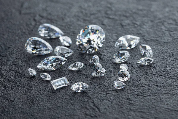 Gepolijste diamanten van verschillende vormen en maten op de werkplek van sieraden expert die de kwaliteit van stenen op donkere achtergrond evalueert met kopieerruimte. — Stockfoto