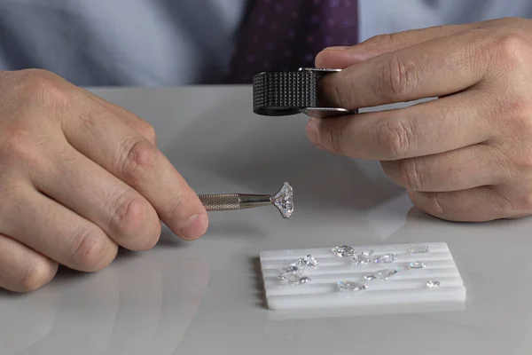 Close up of diamond dealers hands evaluating diamond at international jewelry exhibition — Stock Photo, Image