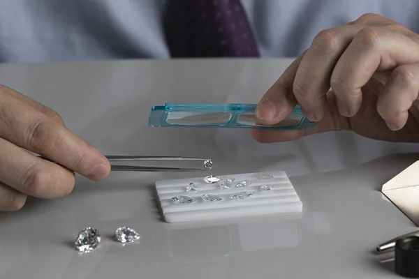 Close up of diamond dealers hands evaluating diamond at international jewelry exhibition — Stock Photo, Image