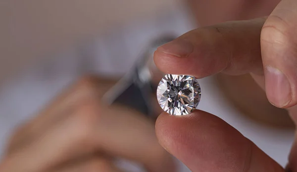 Close up of diamond dealers hands evaluating diamond at international jewelry exhibition — 图库照片