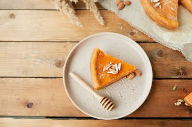 Bademli balkabağı turtası, ballı çubuk ve ahşap masadaki kabak peçeteli turta. Kurumuş çiçekler buketi, seçici odak, üst manzara.